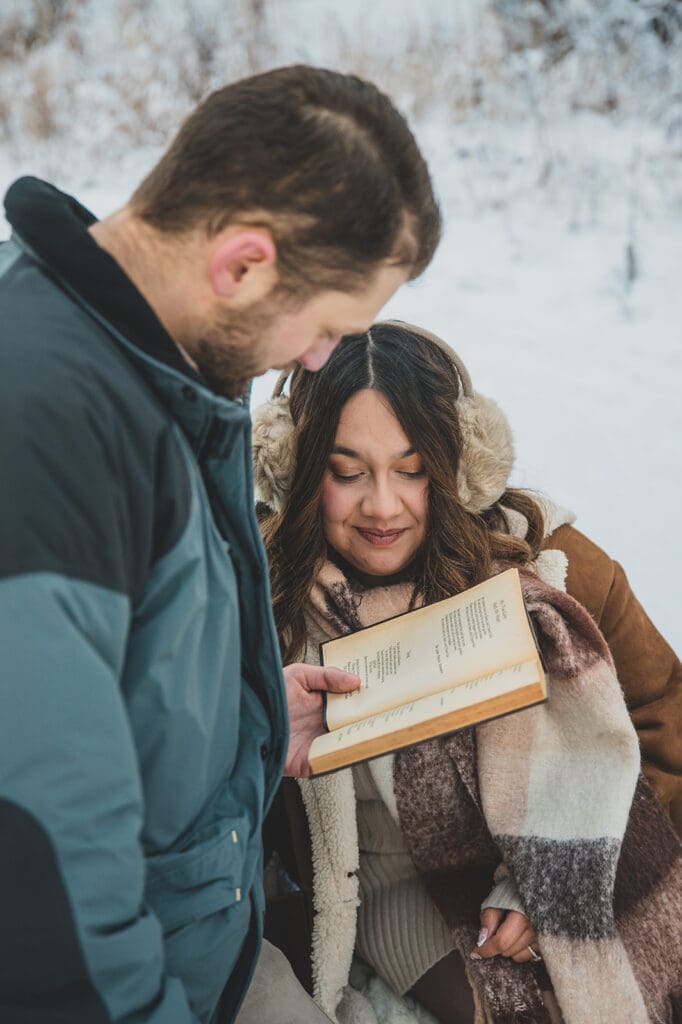couple sharing food during snowy picnic engagement session natural moment