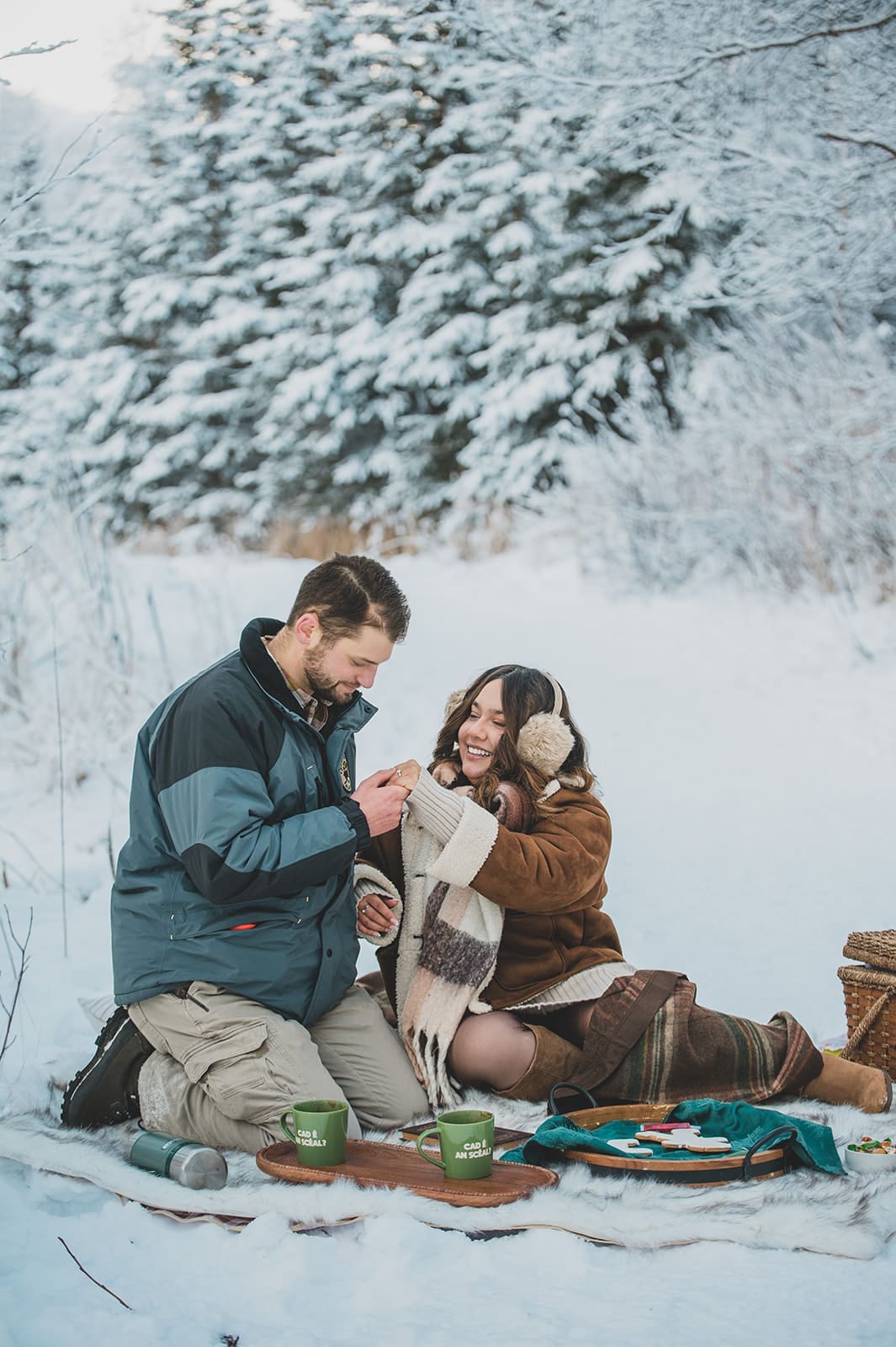 Alaska engagement session couple taking a break with picnic in snowy landscape