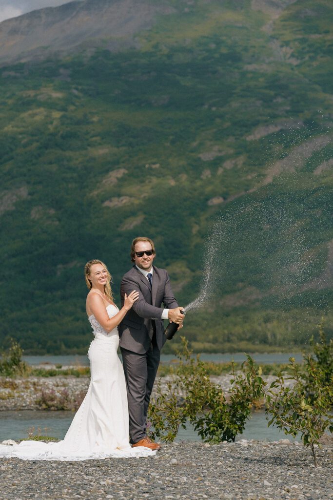 Couple popping champagne during knik river elopement alaska