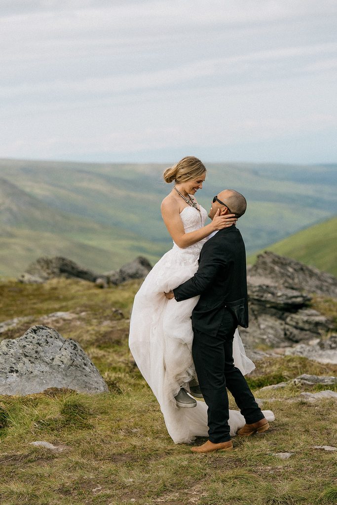 Alt: Bride and groom embracing in the mountains at Hatcher Pass, Alaska