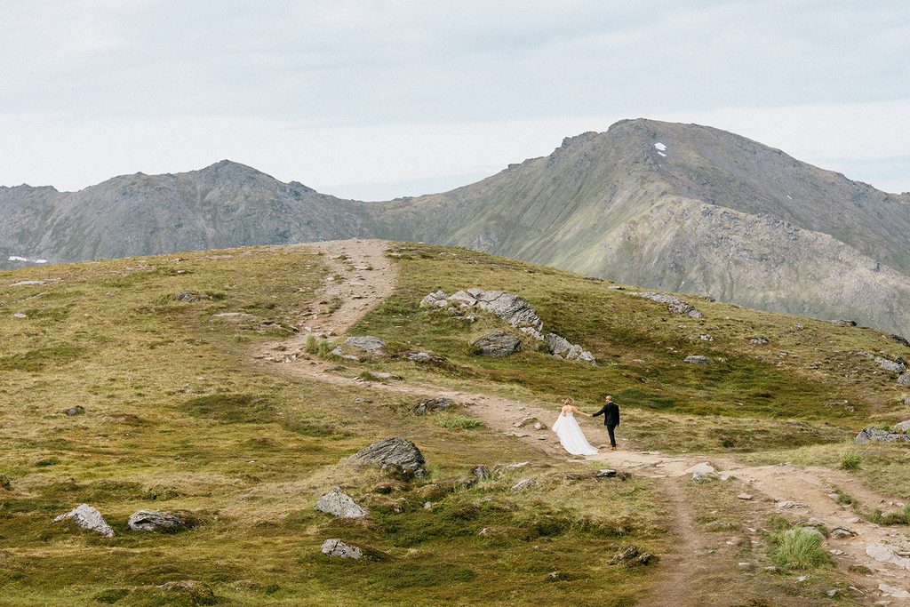 Alt: Bride and groom walking through the mountains during their Hatcher Pass elopement in Alaska