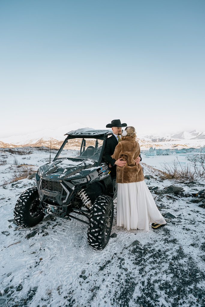 Bride and groom with an off-road vehicle overlooking Knik Glacier during their winter Alaska elopement