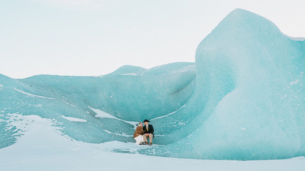 Couple sitting among the blue ice during a Knik Glacier elopement in Alaska